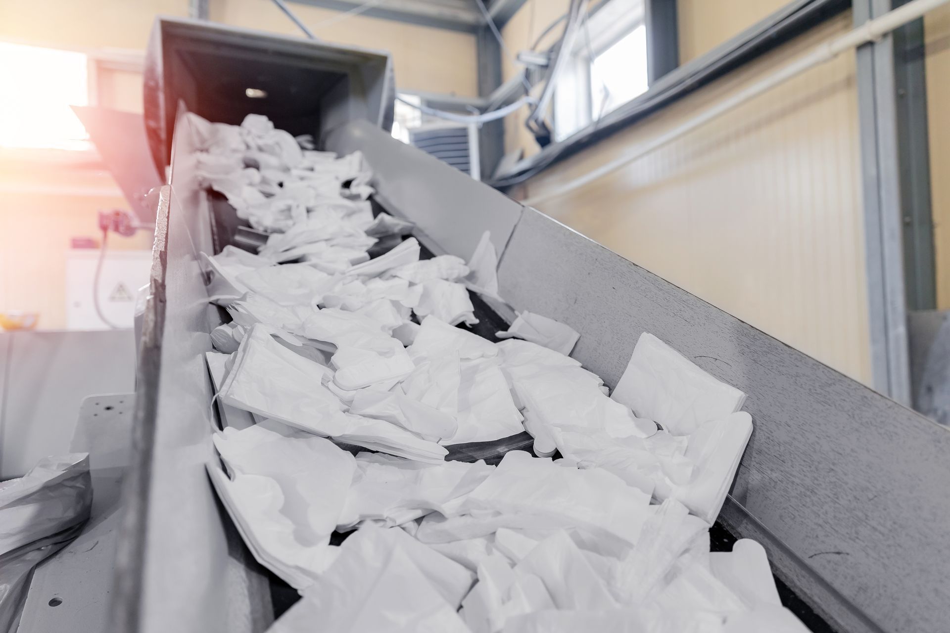 A conveyor belt filled with shredded paper in a factory.