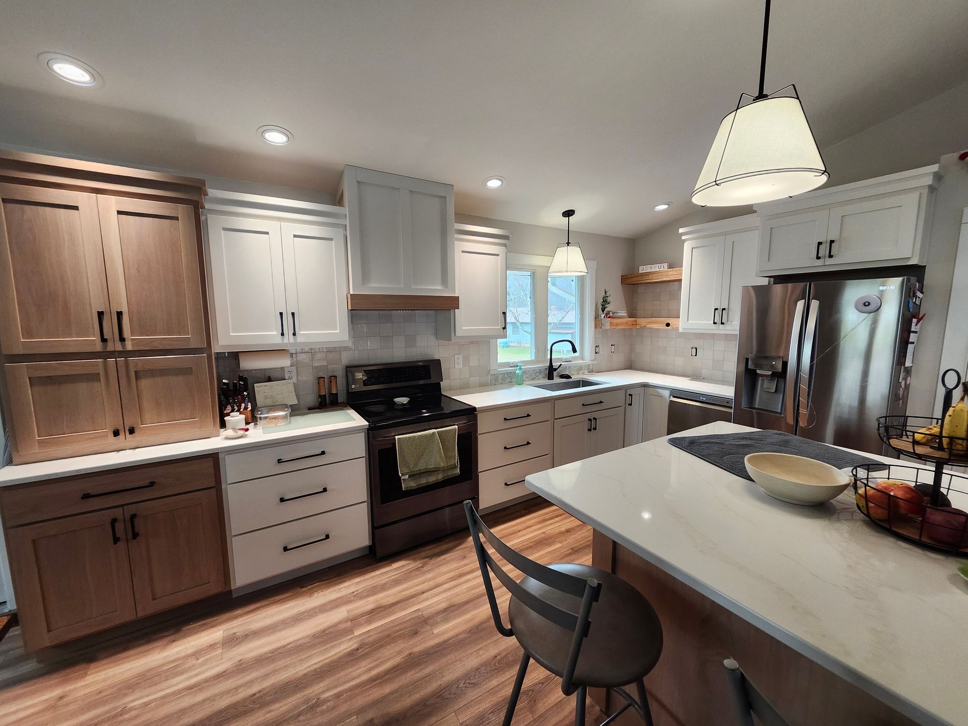 Bright modern kitchen with white cabinets, stainless appliances, island, and wood flooring