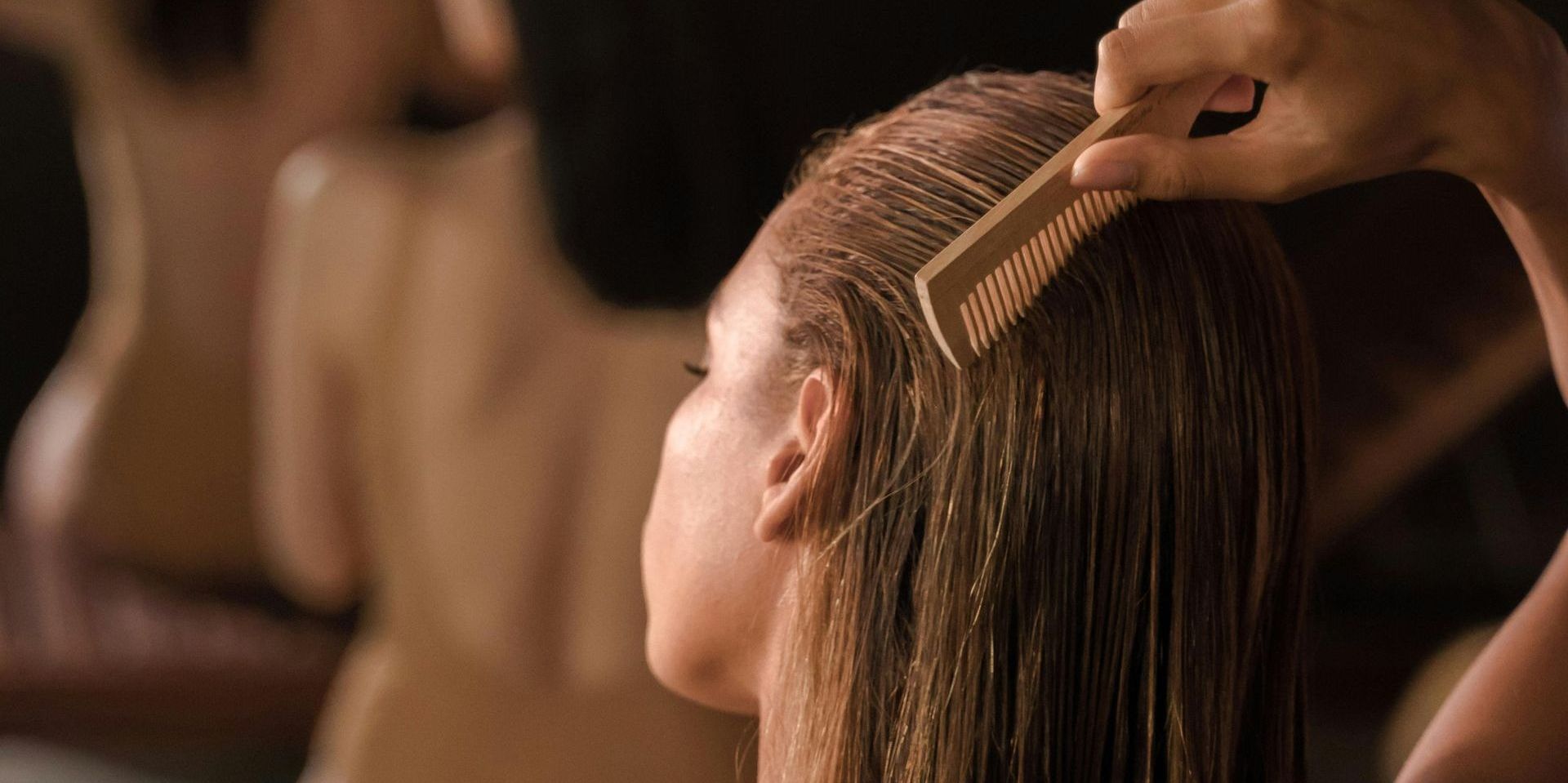 Una donna si spazzola i capelli con un pettine di legno.