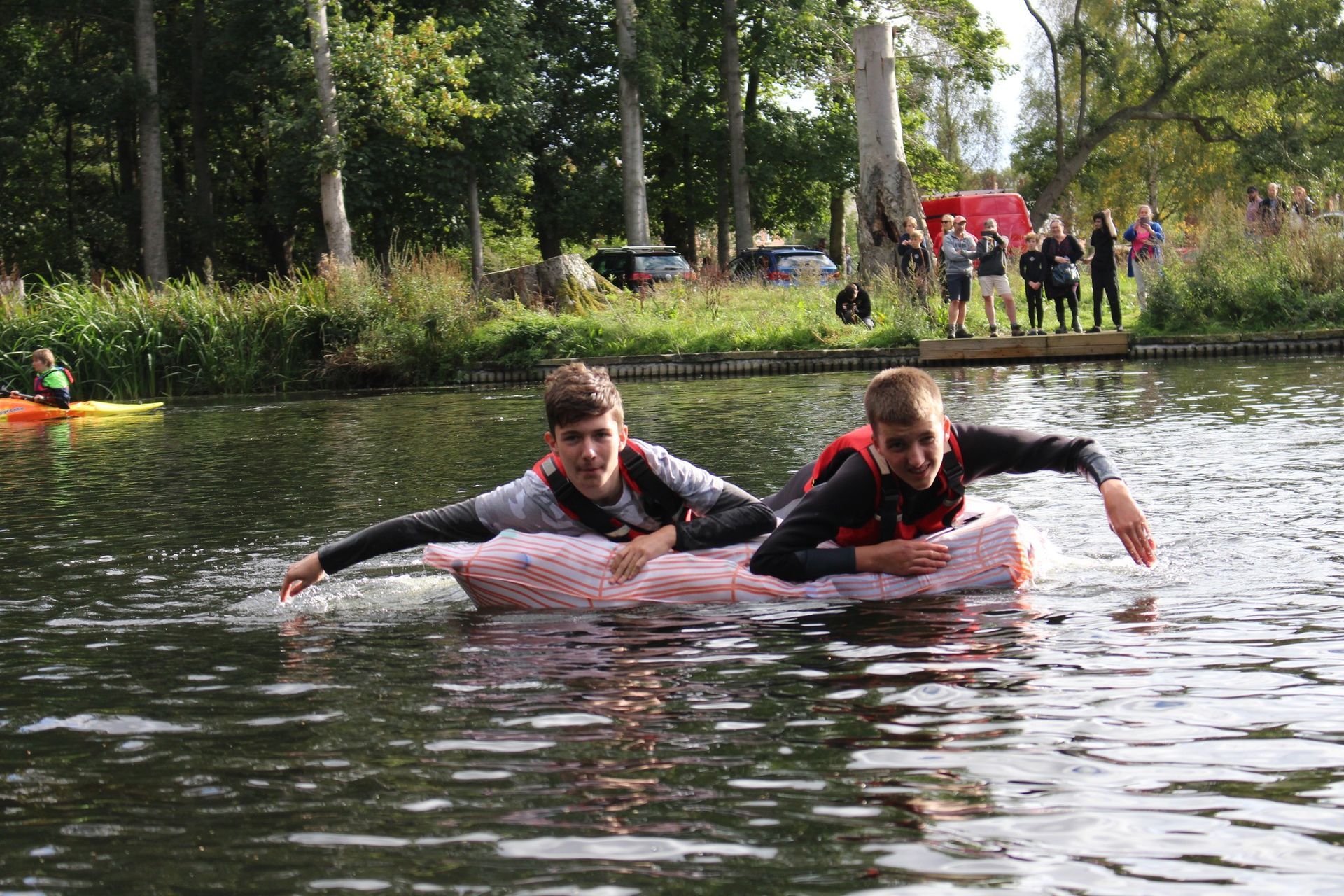 Two Scouts from Lincoln District racing across the water on a homemade raft during a Scouting activity day.