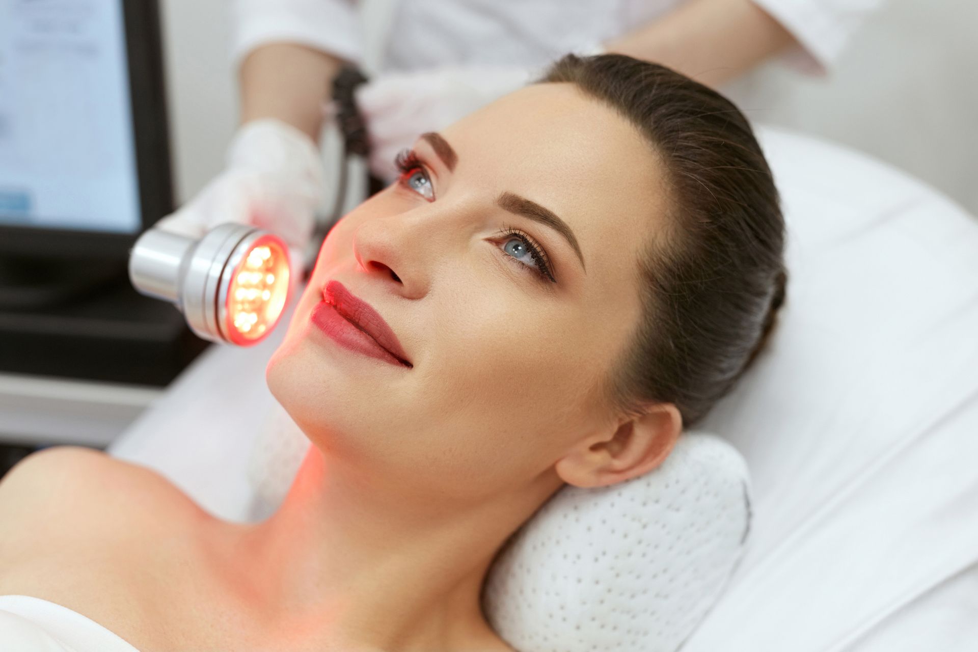 A woman is getting a red light treatment on her face.
