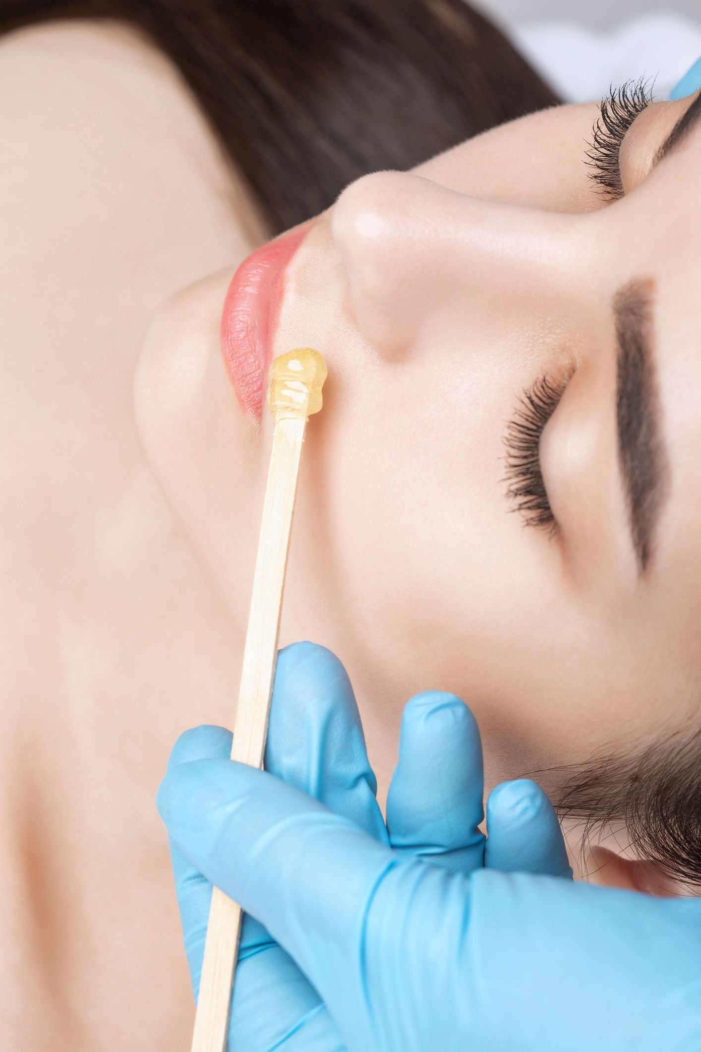A woman is getting a waxing treatment on her face.