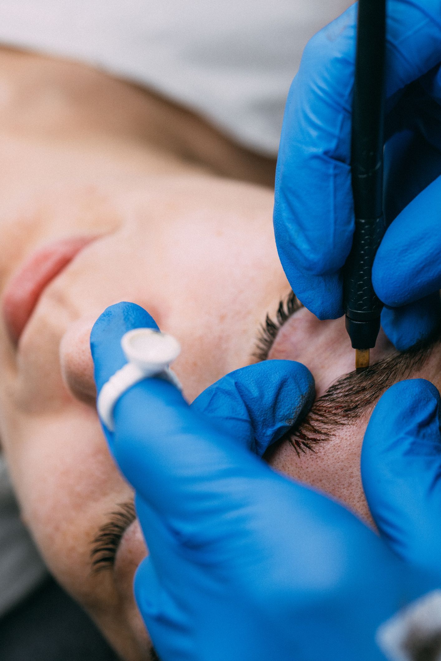 A woman is getting a permanent makeup tattoo on her eyebrows.