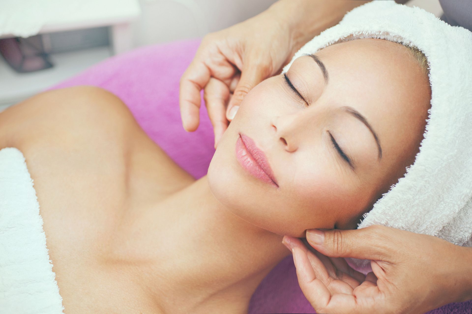A woman is getting a facial massage at a spa.