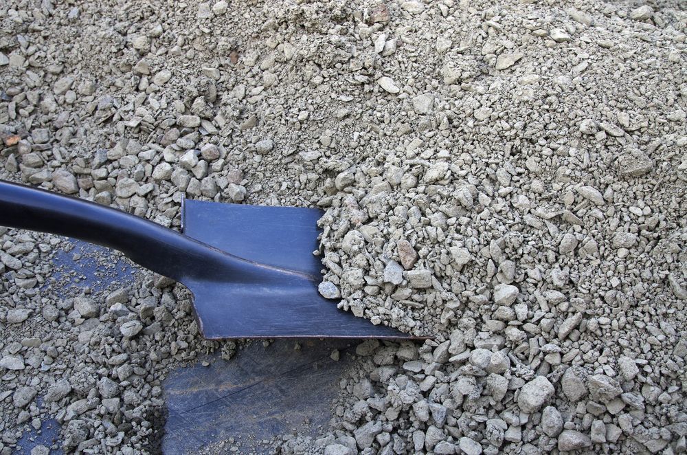 Black Shovel Scooping Gravel on a Rocky Surface — King Reef Concrete in Kurrimine Beach, QLD