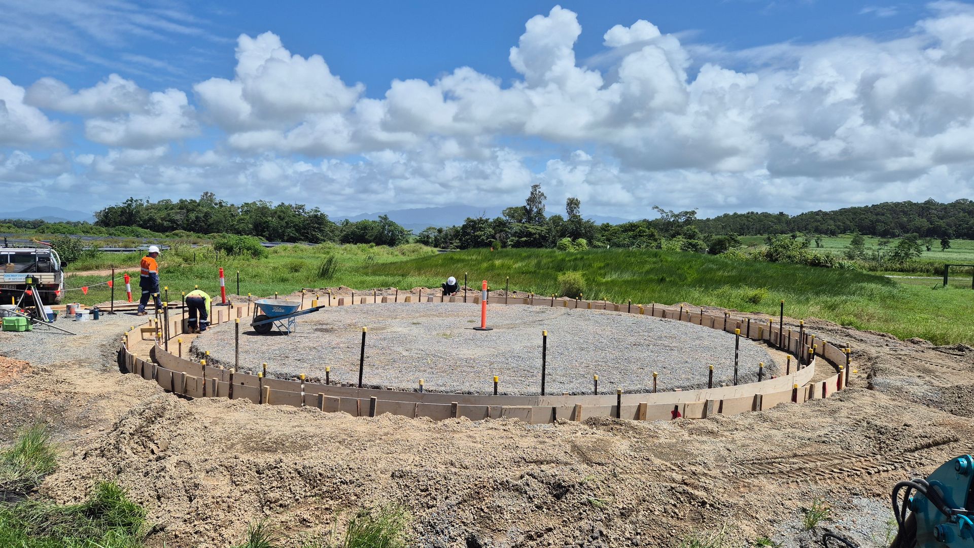 Construction site with a circular concrete foundation in a grassy field under a cloudy sky — King Reef Concrete in Kurrimine Beach, QLD