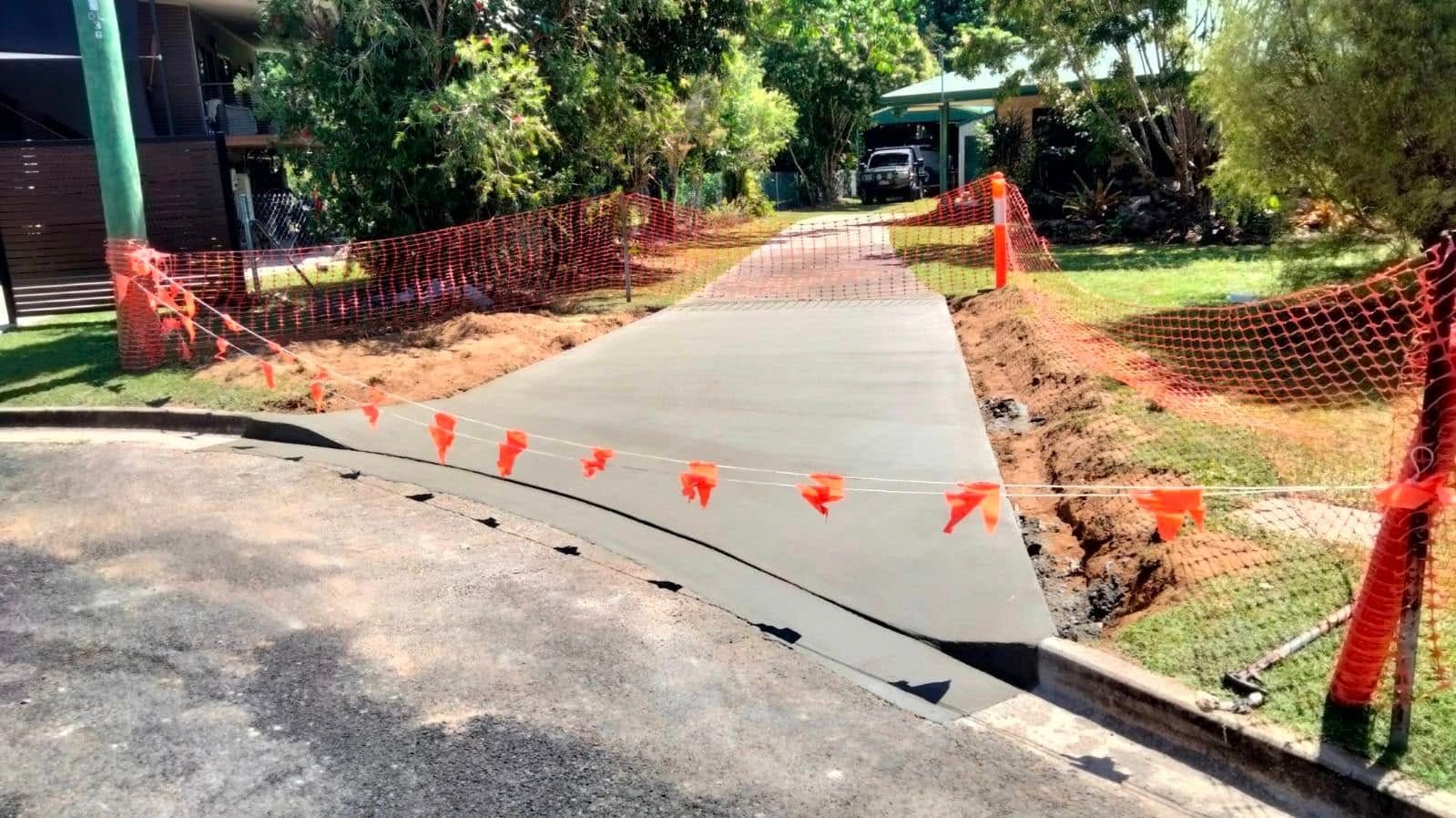 Concrete sidewalk under construction beside a road, lined with orange safety fencing and cones. — King Reef Concrete in Kurrimine Beach, QLD