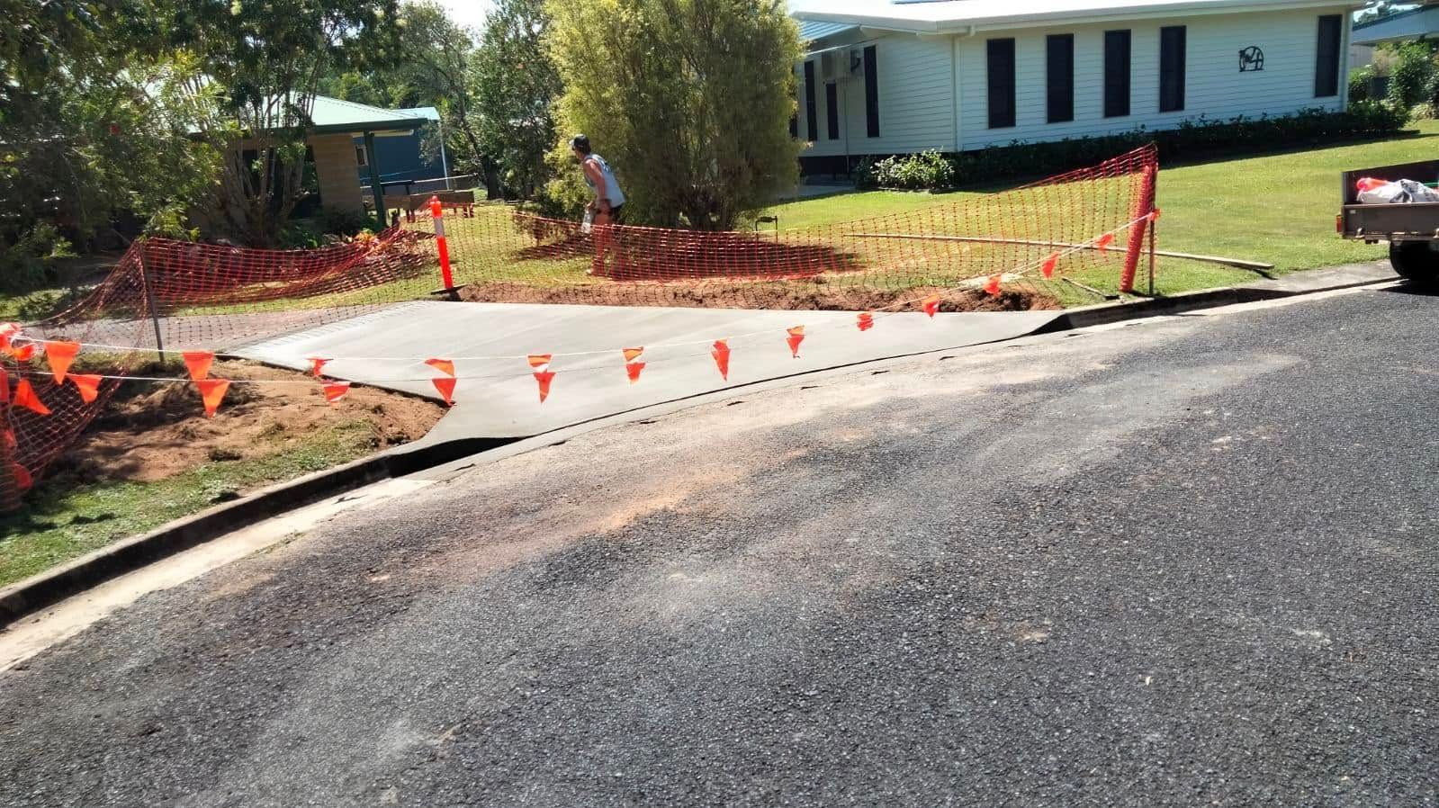 Construction cones and orange caution tape blocking a driveway beside a house and paved road. — King Reef Concrete in Kurrimine Beach, QLD