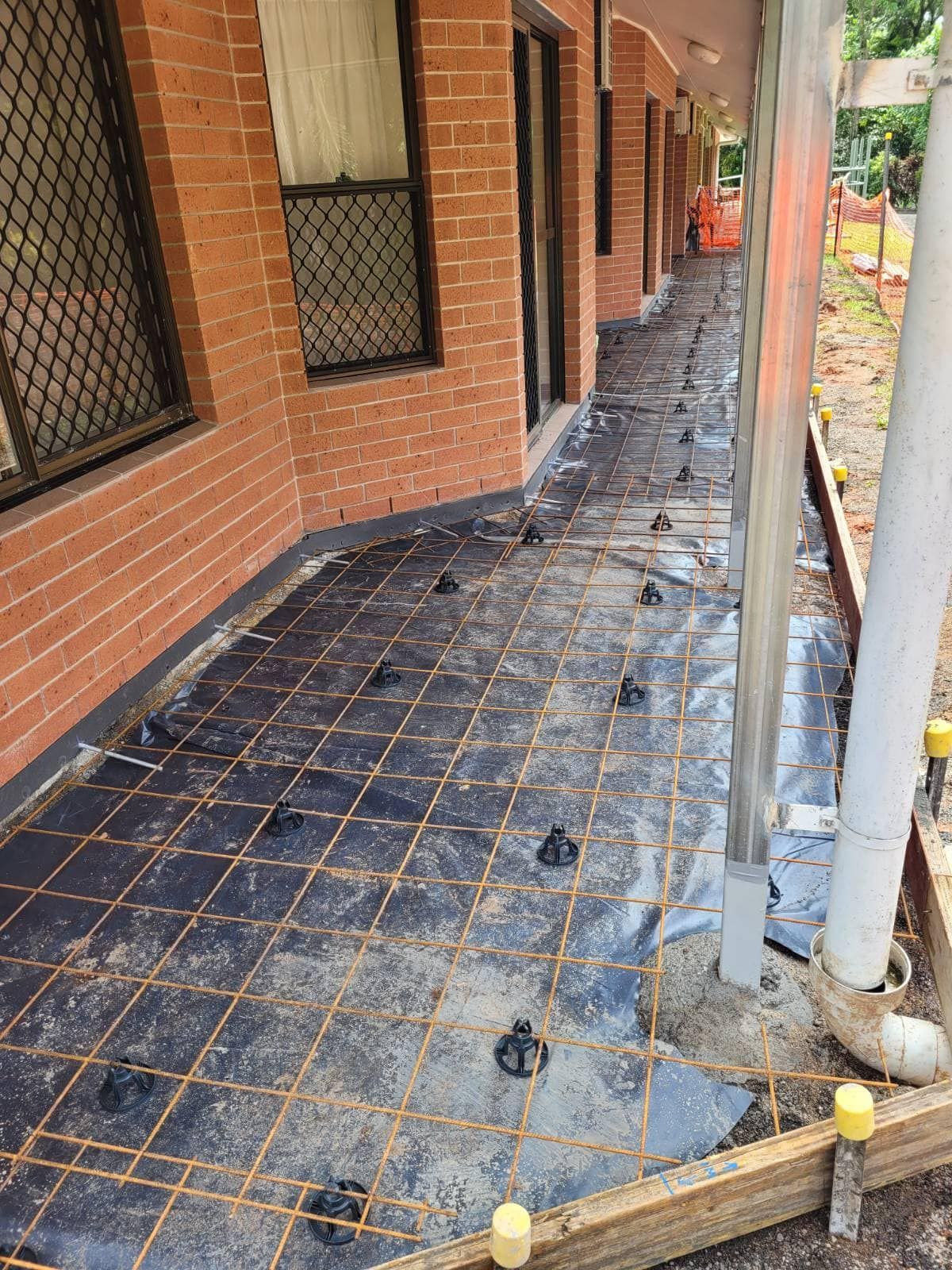 Construction Worker Pouring Concrete Onto Rebar at a Building Site — King Reef Concrete in Innisfail, QLD