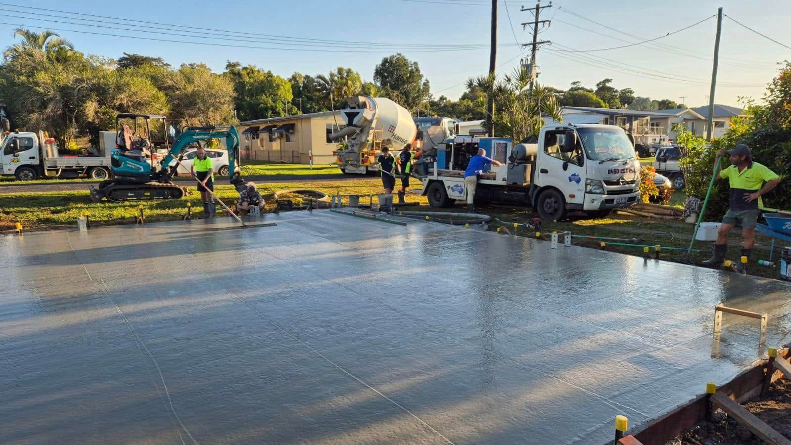 Concrete being poured on a road by workers with a cement mixer truck at a construction site
