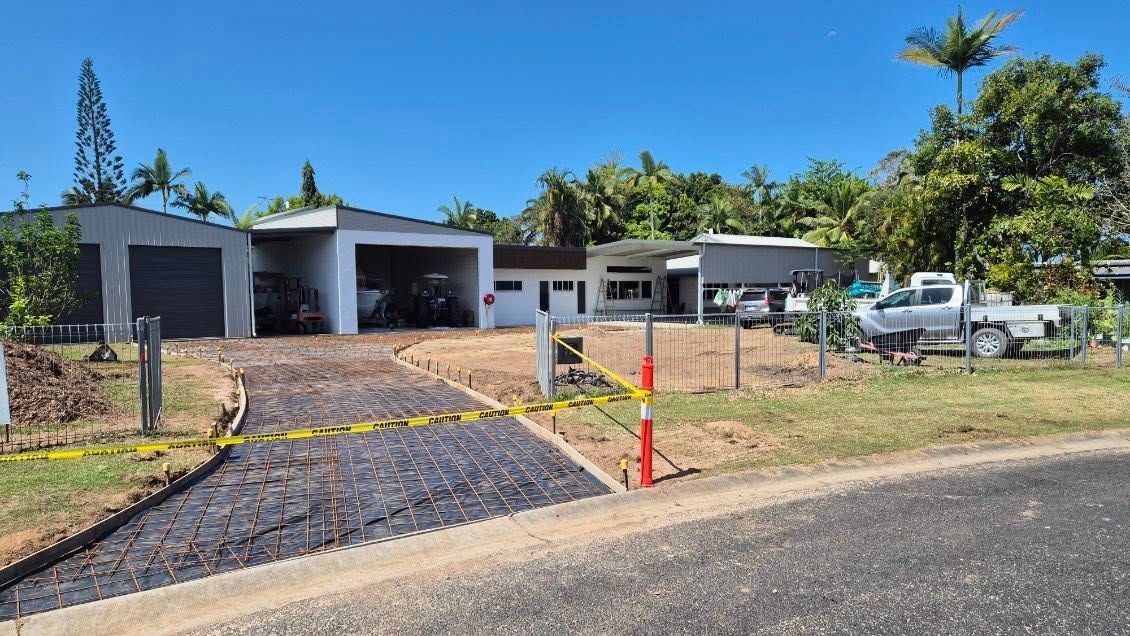 Suburban house with driveway under construction, orange cones, and parked vehicles on a sunny day — King Reef Concrete in Kurrimine Beach, QLD