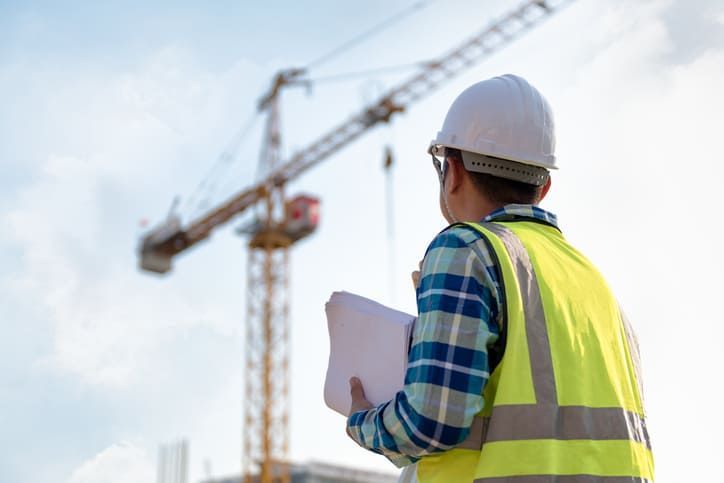 Un operaio edile osserva una gru in un cantiere.