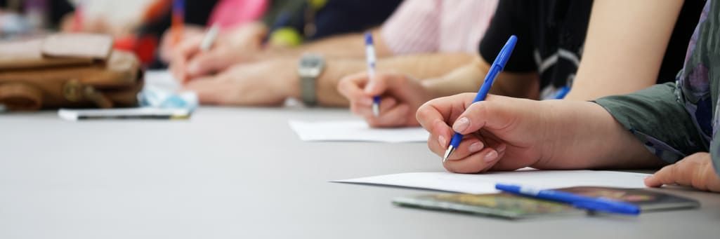 Un gruppo di persone è seduto a un tavolo e scrive su un pezzo di carta.
