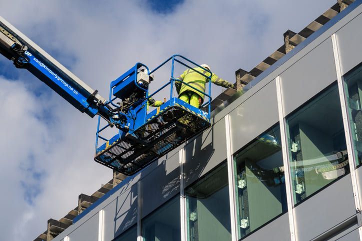 Un uomo sta lavorando sul lato di un edificio con una gru.