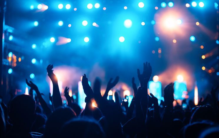 Una folla di persone alza le mani in aria durante un concerto.