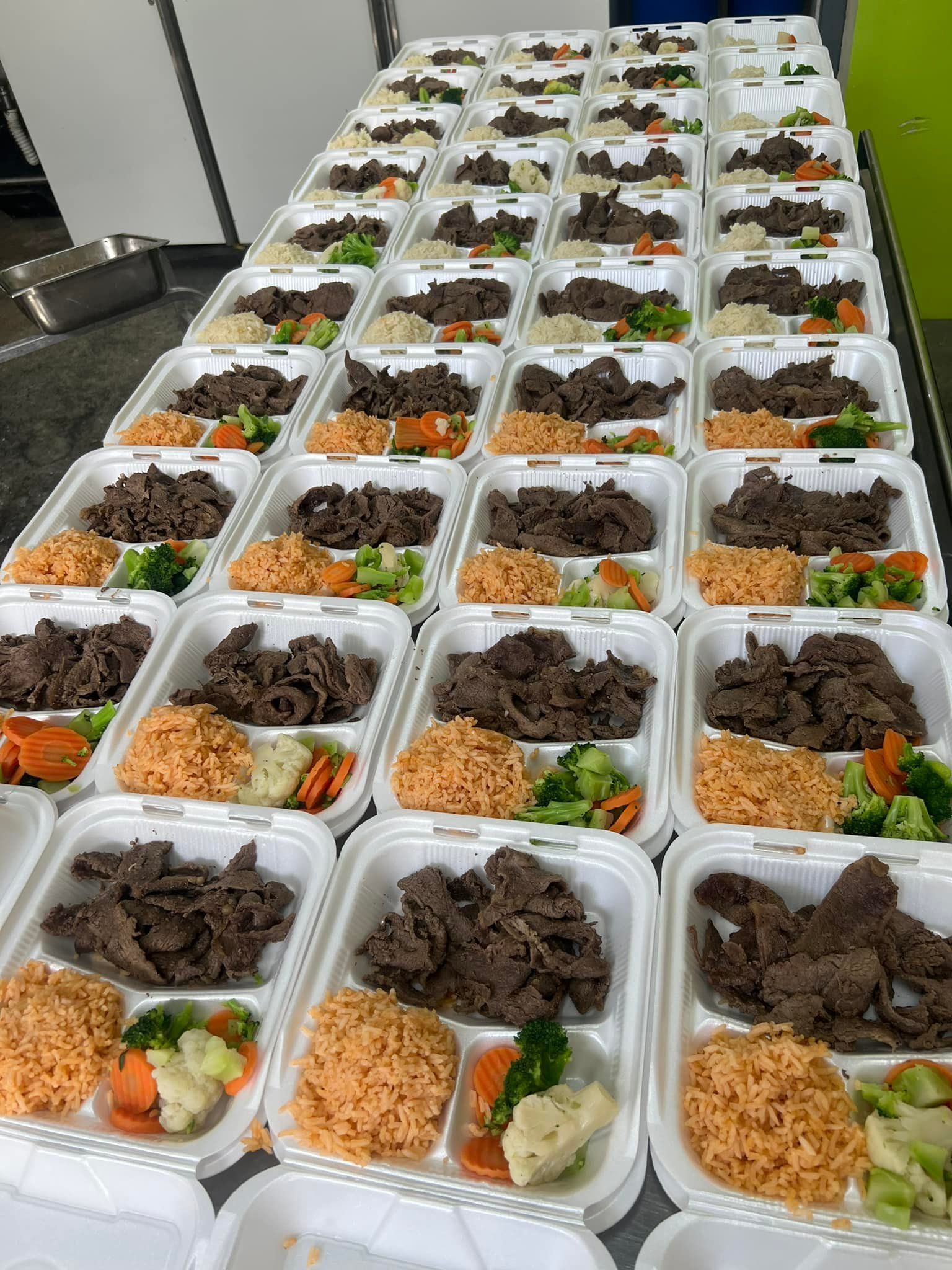 Many white divided containers, each filled with slices of dark meat, orange rice, and a small side of cooked vegetables.