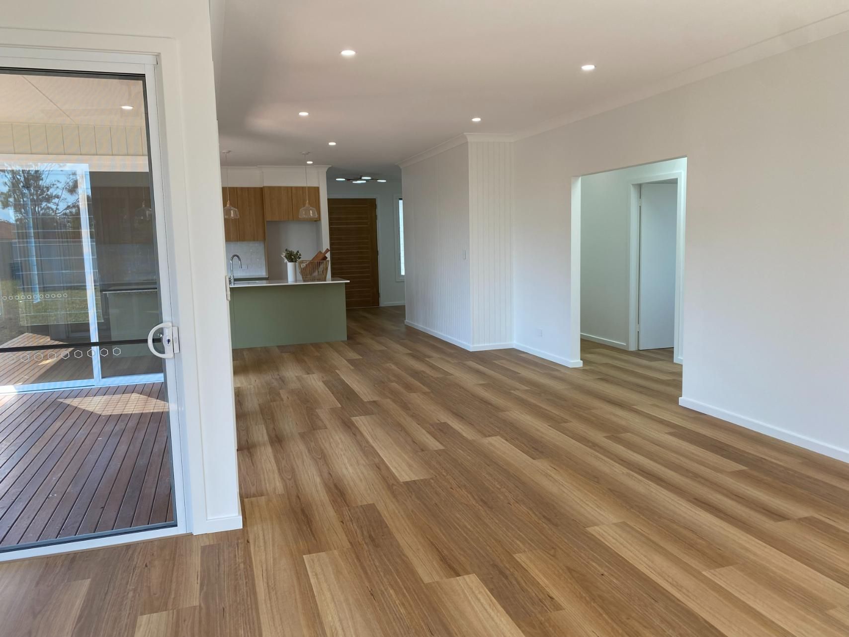 Empty Living Room With Wood Floor and View Into Kitchen — Mid North Coast Drafting & Construction in Taree, NSW