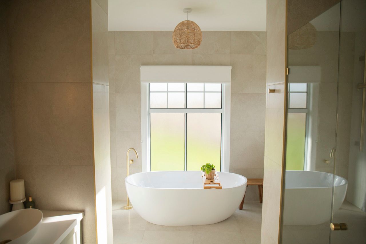 White Soaking Tub in Bathroom With Beige Tile and Pendant Light — Mid North Coast Drafting & Construction in Taree, NSW