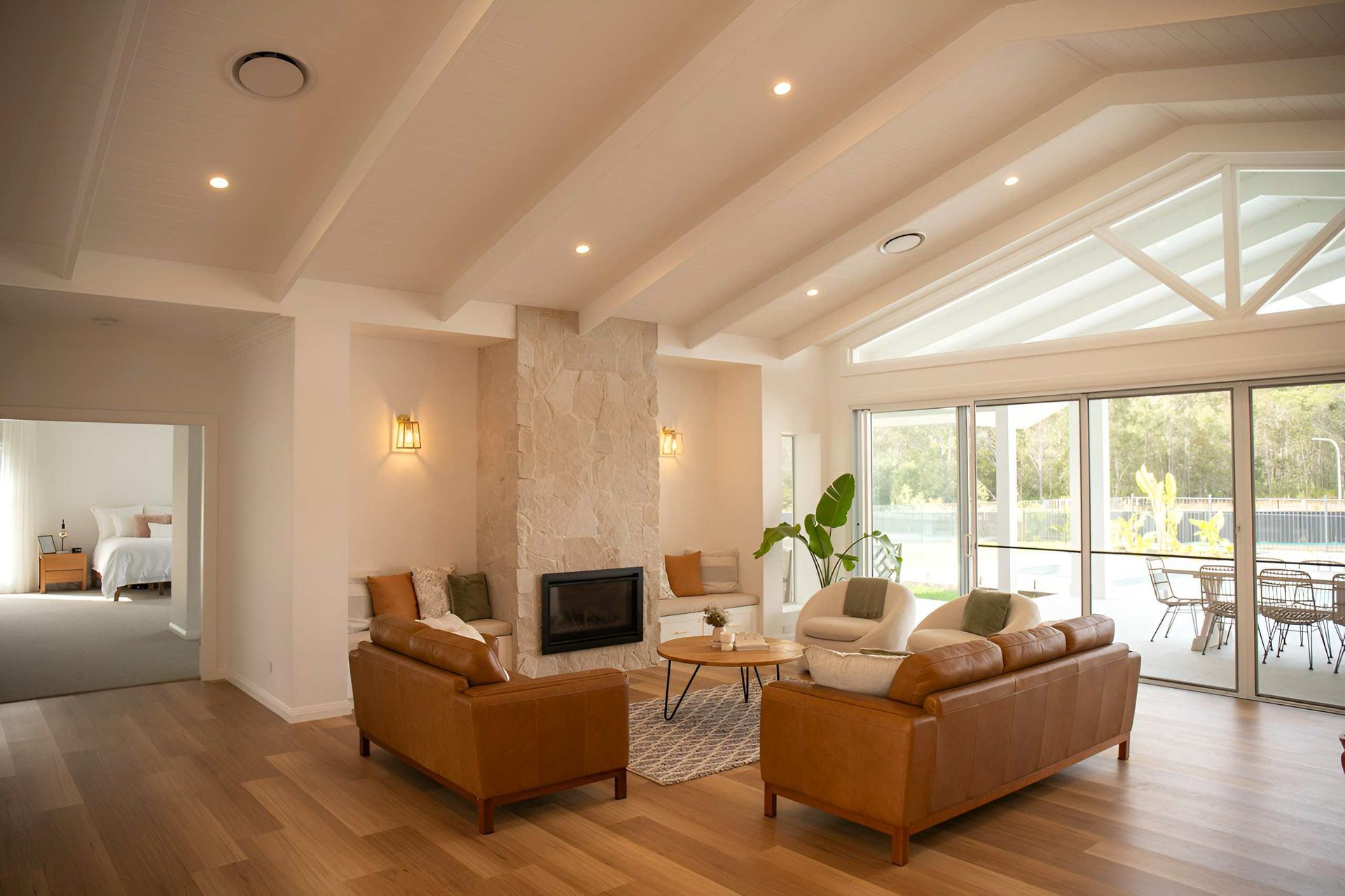 A spacious living room with a fireplace and leather sofas, showcasing a home designed by a Builder Taree service in Taree, NSW.