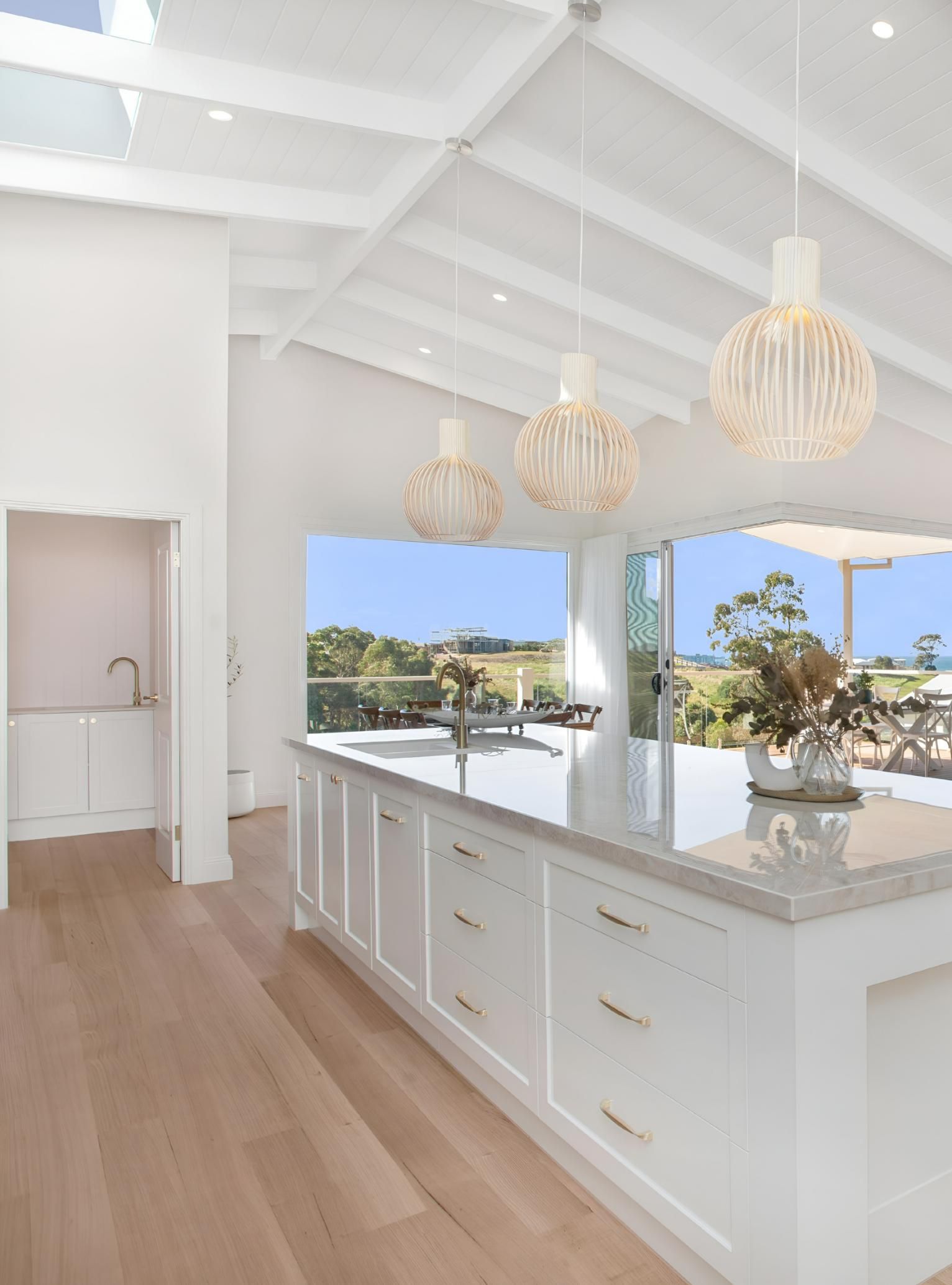 White Kitchen With Island, Pendant Lights and Wooden Floor — Mid North Coast Drafting & Construction in Harrington, NSW