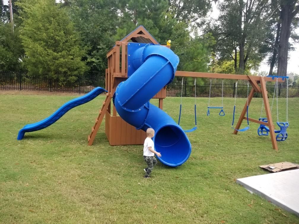 Child near blue playground slide in a grassy park