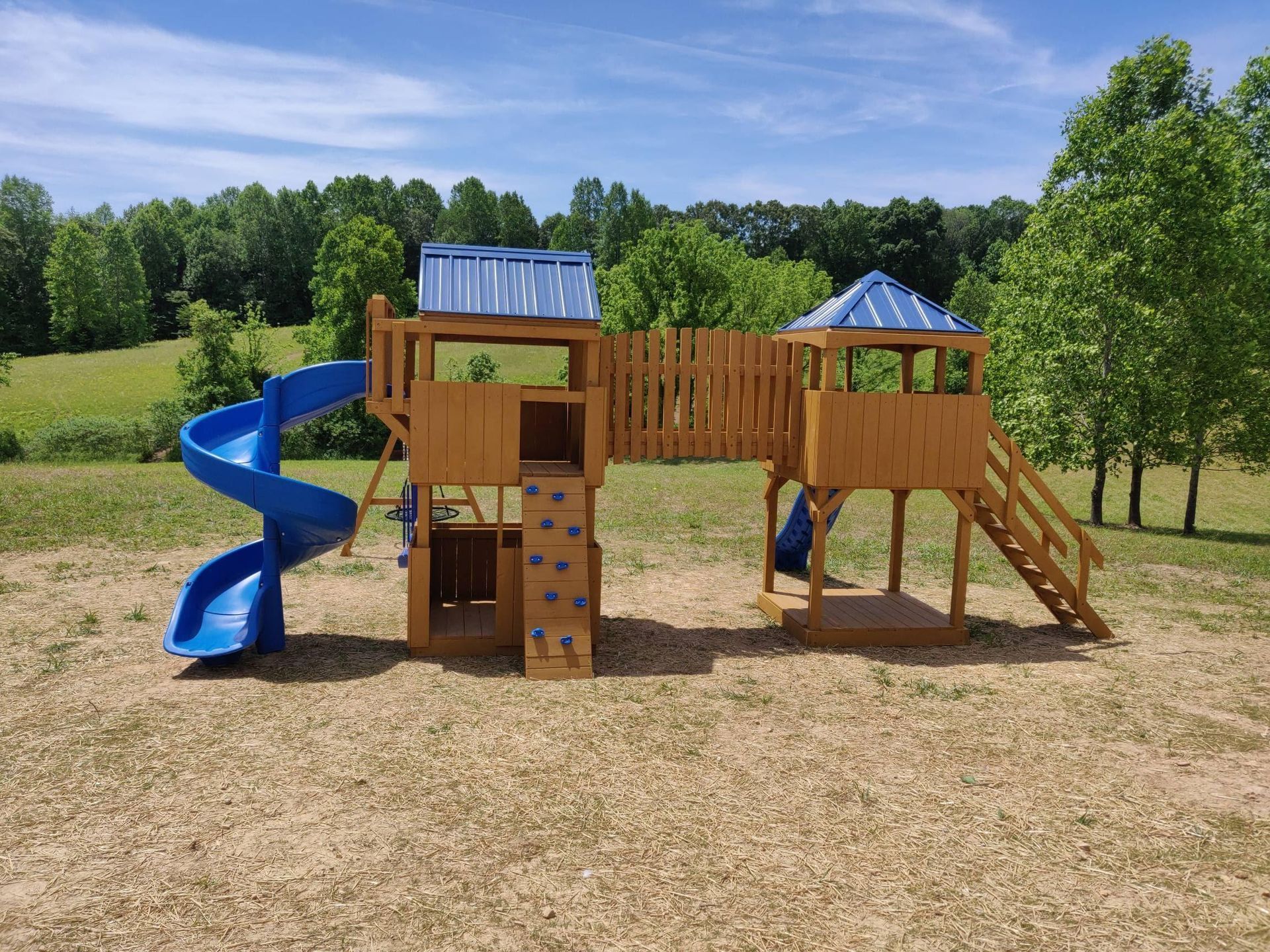 Children’s playground with blue slide, wooden climbing structure, and grassy park setting