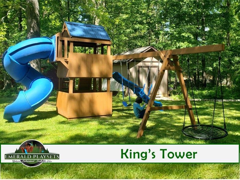 Play set: wooden tower with blue slide, swing set, net swing, green lawn, trees.