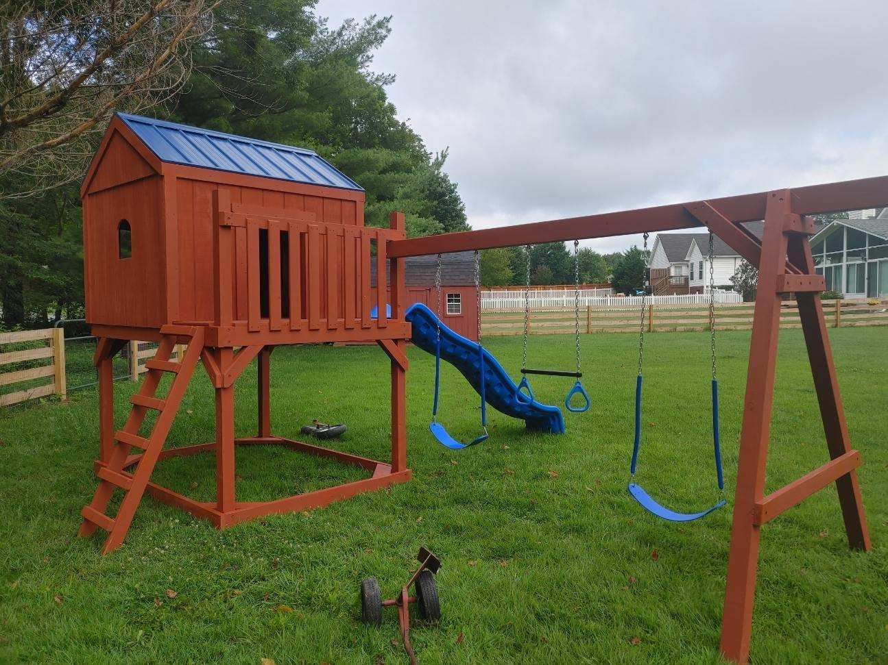 Wooden backyard playset with slide, swings, and climbing ladder on a grassy field