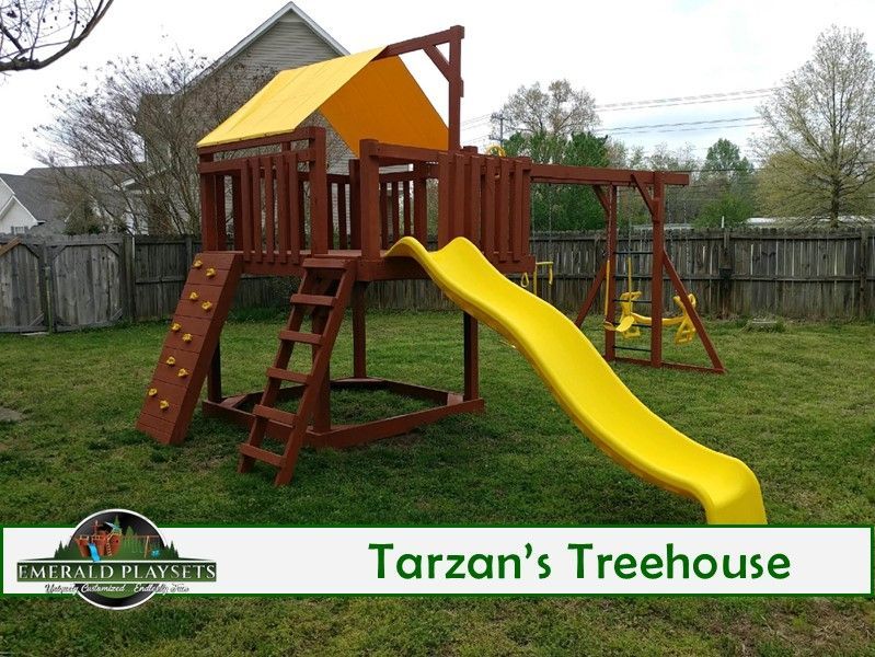 Playground set with a yellow slide, swings, and climbing wall; brown wood construction.