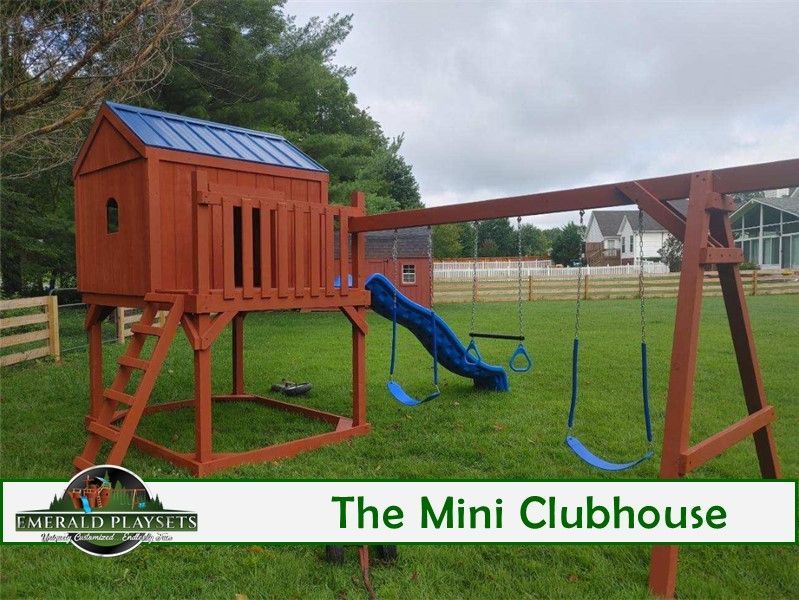 Wooden playground set with clubhouse, slide, and swings on green grass.