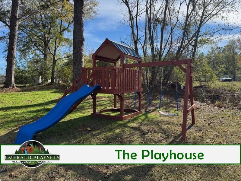 A wooden playhouse with a blue slide and swings