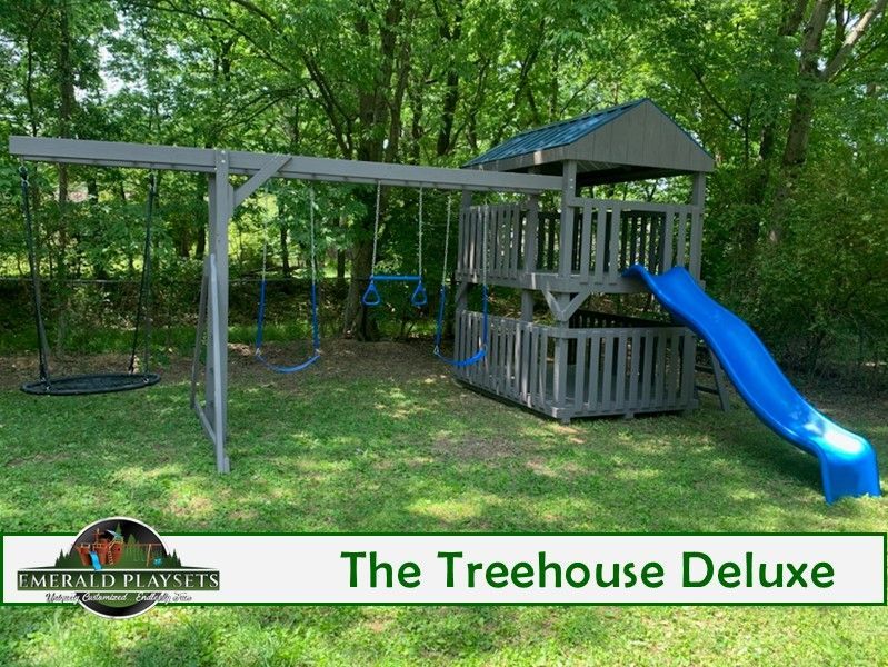 A treehouse deluxe playground with a blue slide and swings