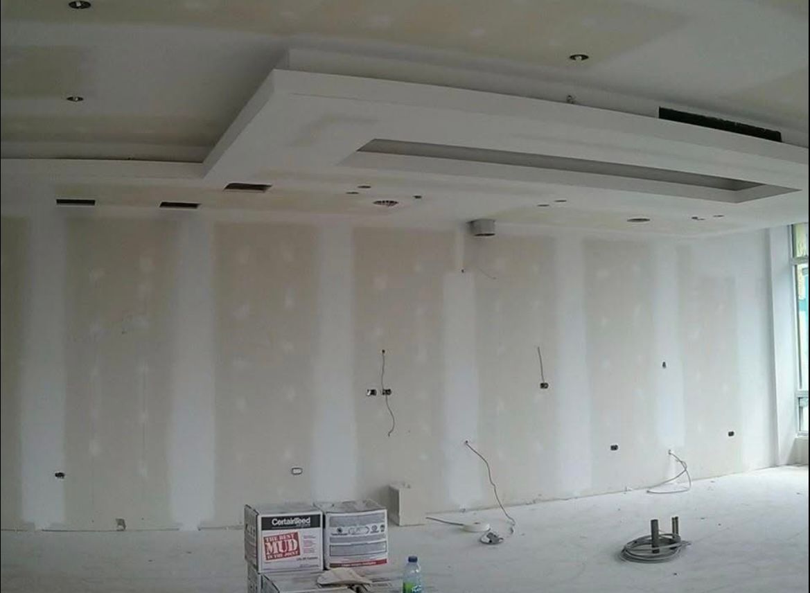 Pièce intérieure en travaux, murs et plafond en plaques de plâtre. Câbles et boîtes électriques visibles.