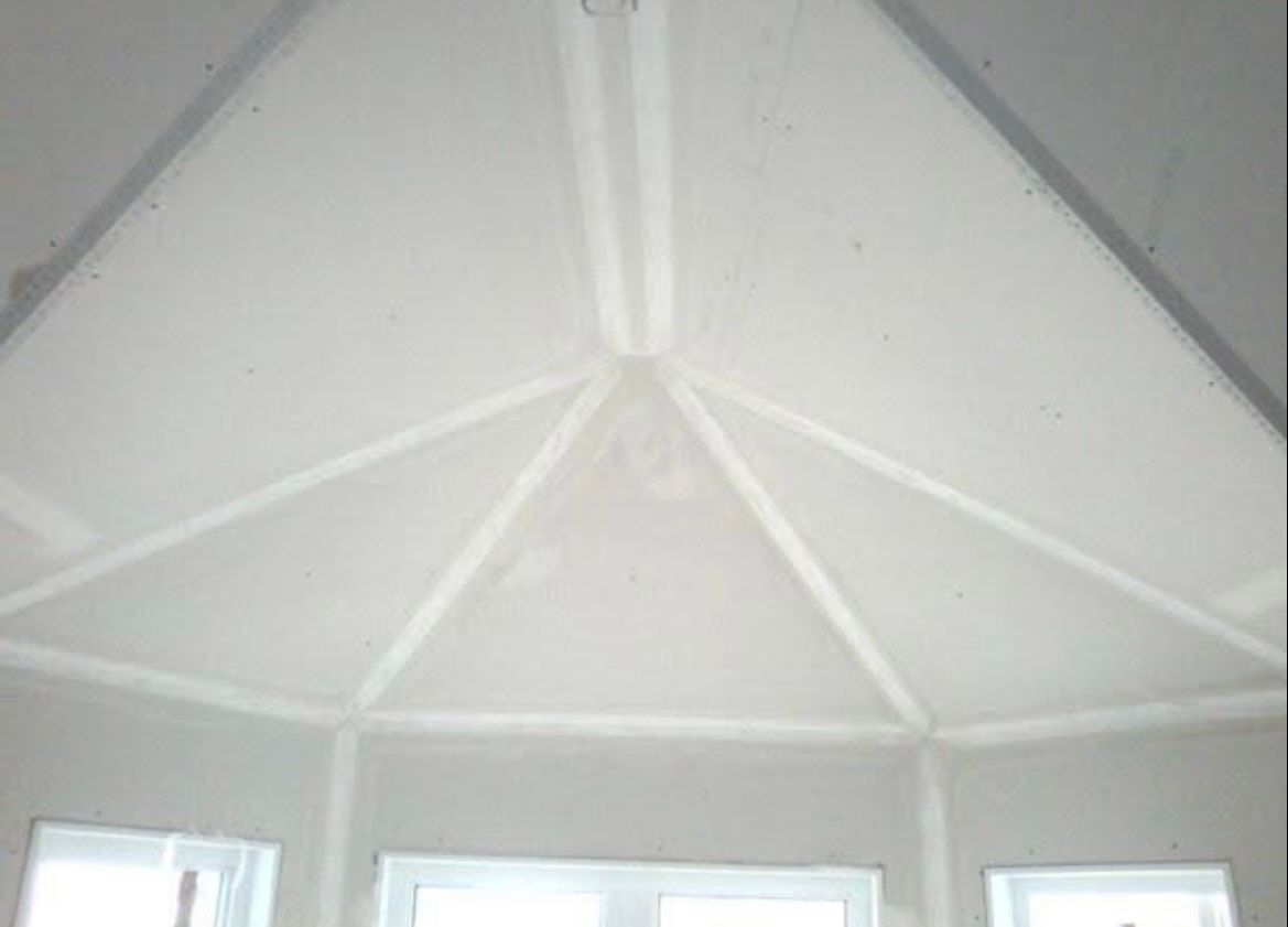 Plafond blanc en pente avec panneaux et joints géométriques.