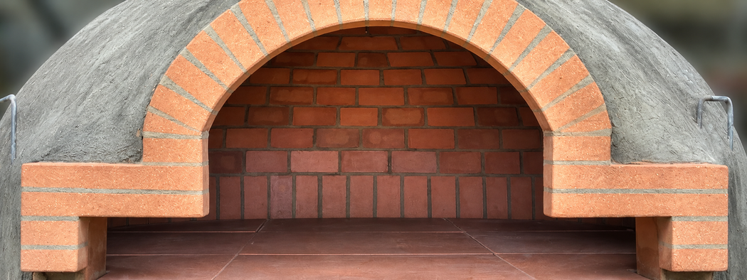 Camino da esterno in mattoni con apertura ad arco e cornice in pietra grigia.