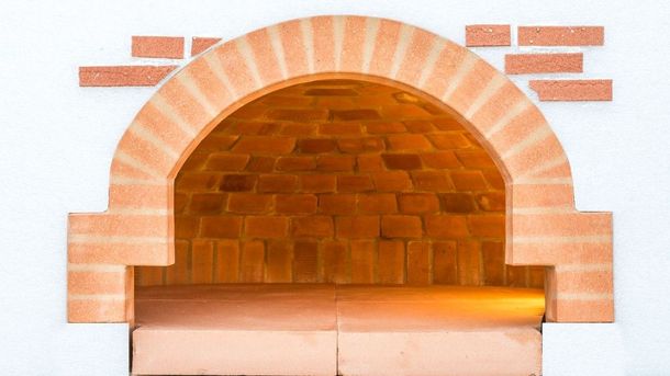 Forno ad arco in mattoni con mattoni arancioni e fuoco ardente all'interno