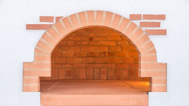 Camino ad arco in mattoni con mensola in legno e calda luce arancione all'interno
