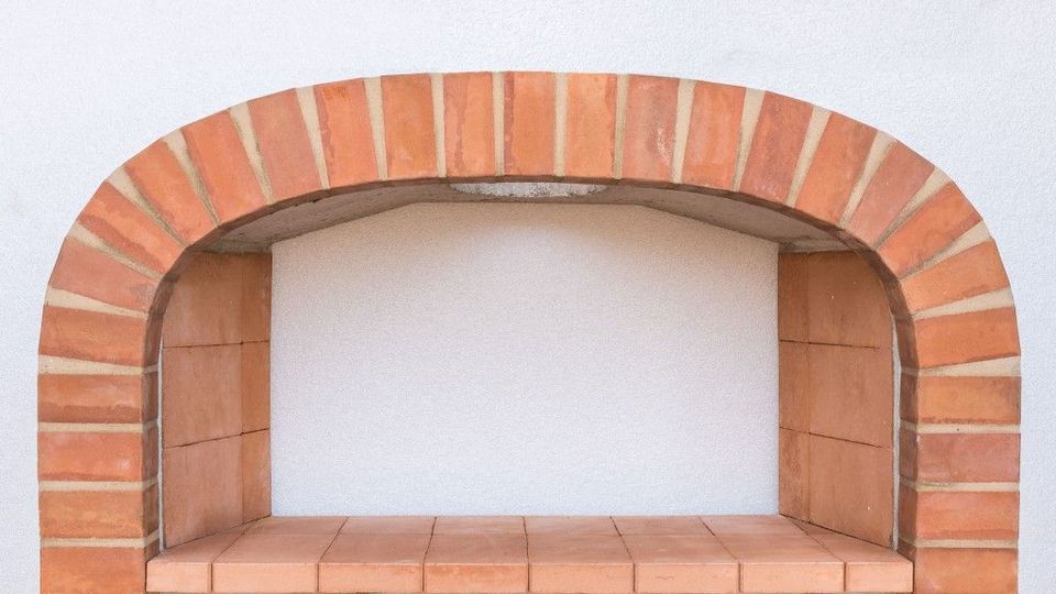 Camino in mattoni a vista con apertura ad arco e parete interna bianca.