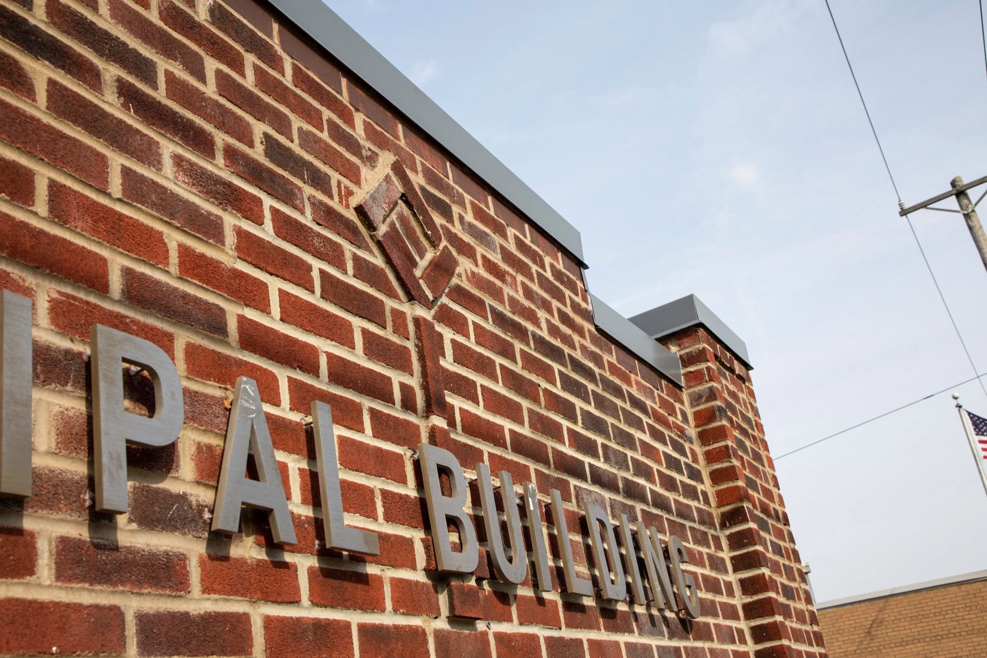 Brick building wall with large metal letters spelling “PAL BUILDIN…” under a cloudy sky