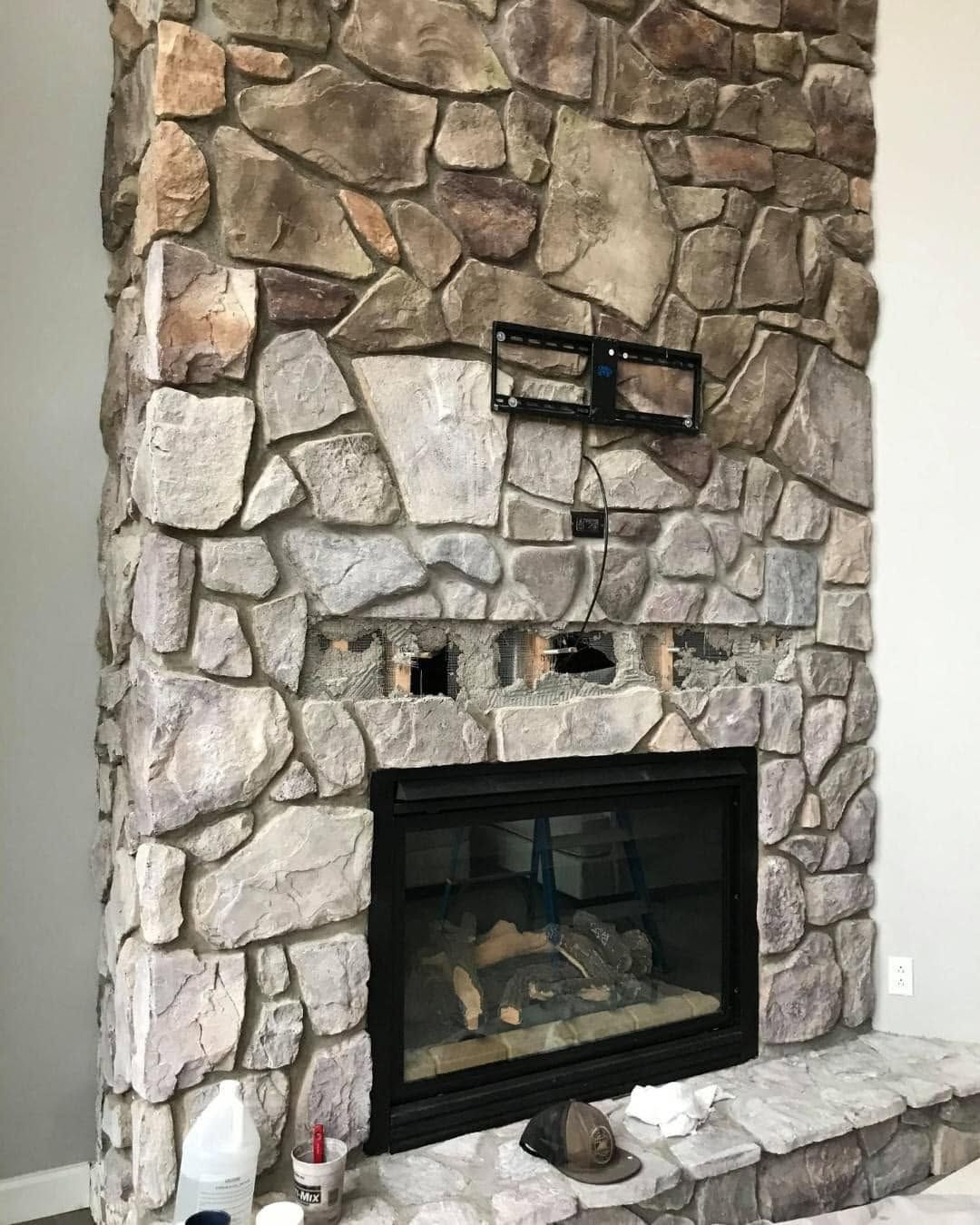 Stone fireplace with black glass firebox and a small wall-mounted TV bracket above it