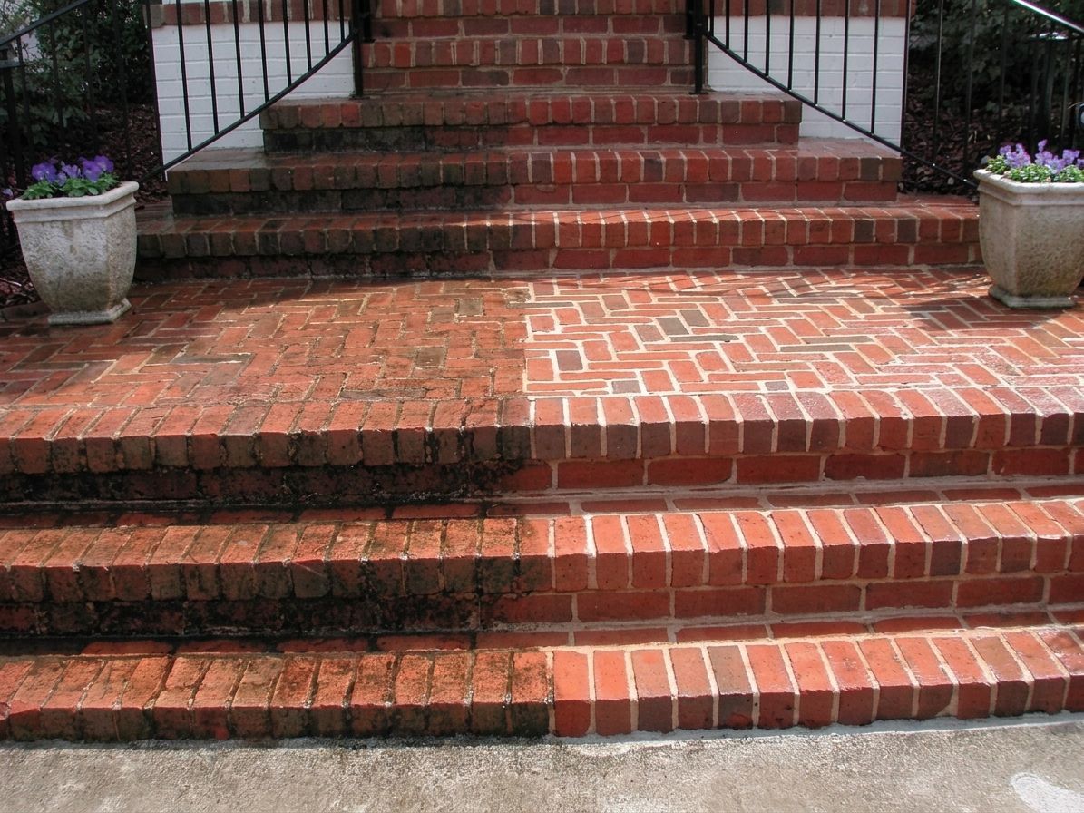 Red brick steps leading to a front porch, with flower pots on both sides
