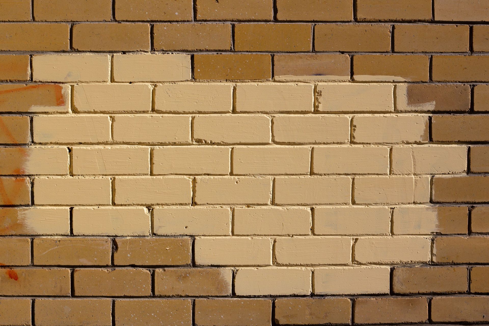 Red brick wall with a beige lintel above a window and a black outdoor lantern on the left