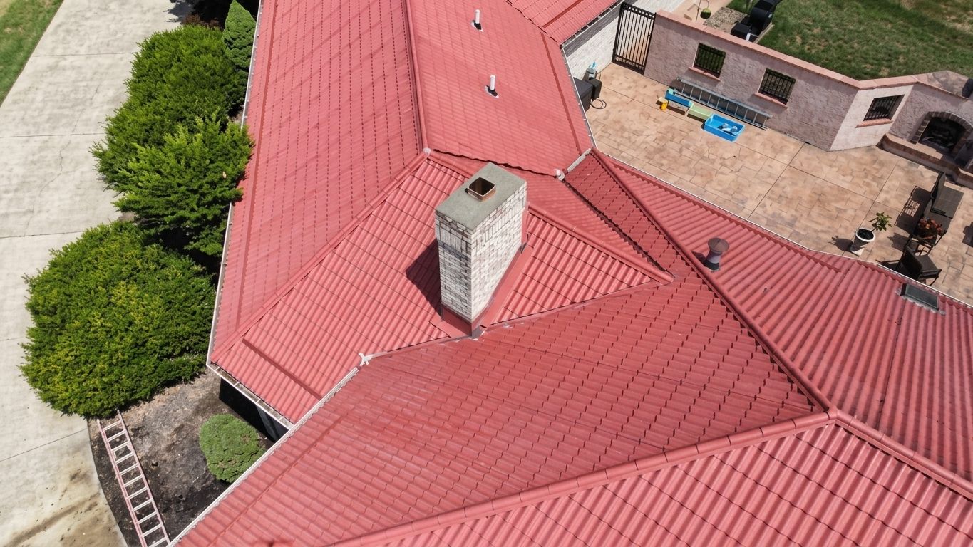 Aerial view of red-roofed buildings with a small chimney and green trees nearby