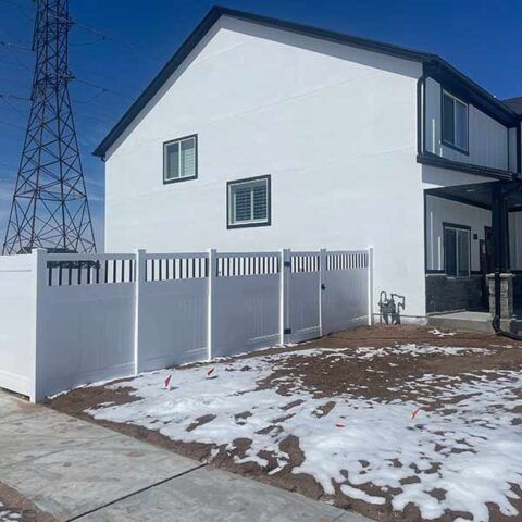 White two-story house with a new gray fence, snowy yard, and power lines beside it