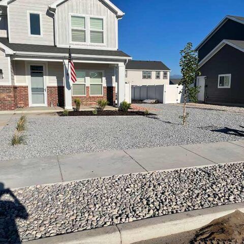Suburban house with gravel front yard, American flag, and garage on a sunny day