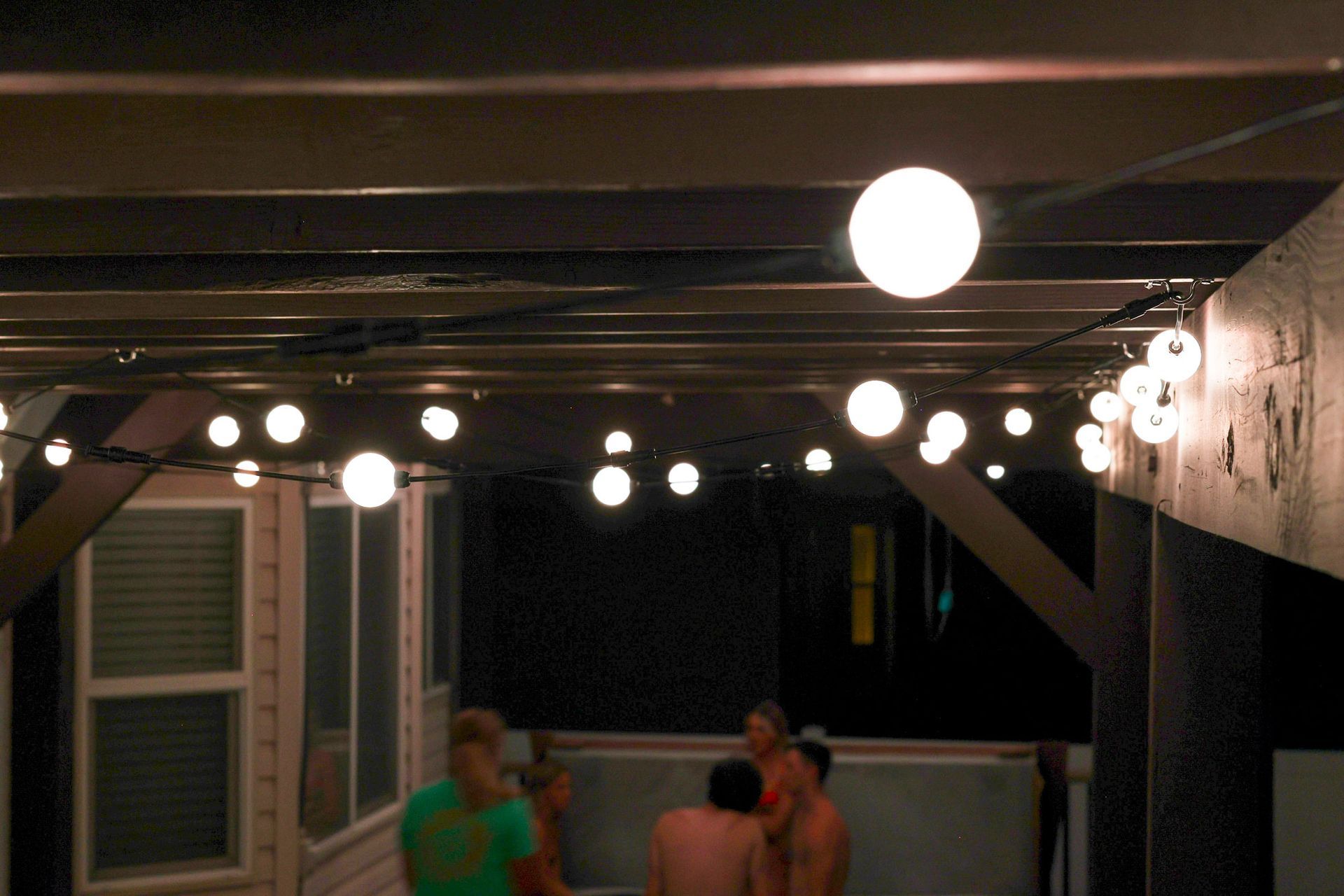 A group of people standing under a string of lights