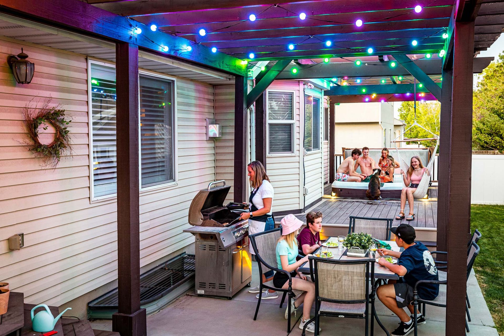 A group of people are sitting at a table under a pergola.