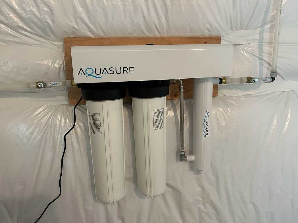 Aquasure water filtration system with two white filter cartridges mounted on a wall-mounted unit