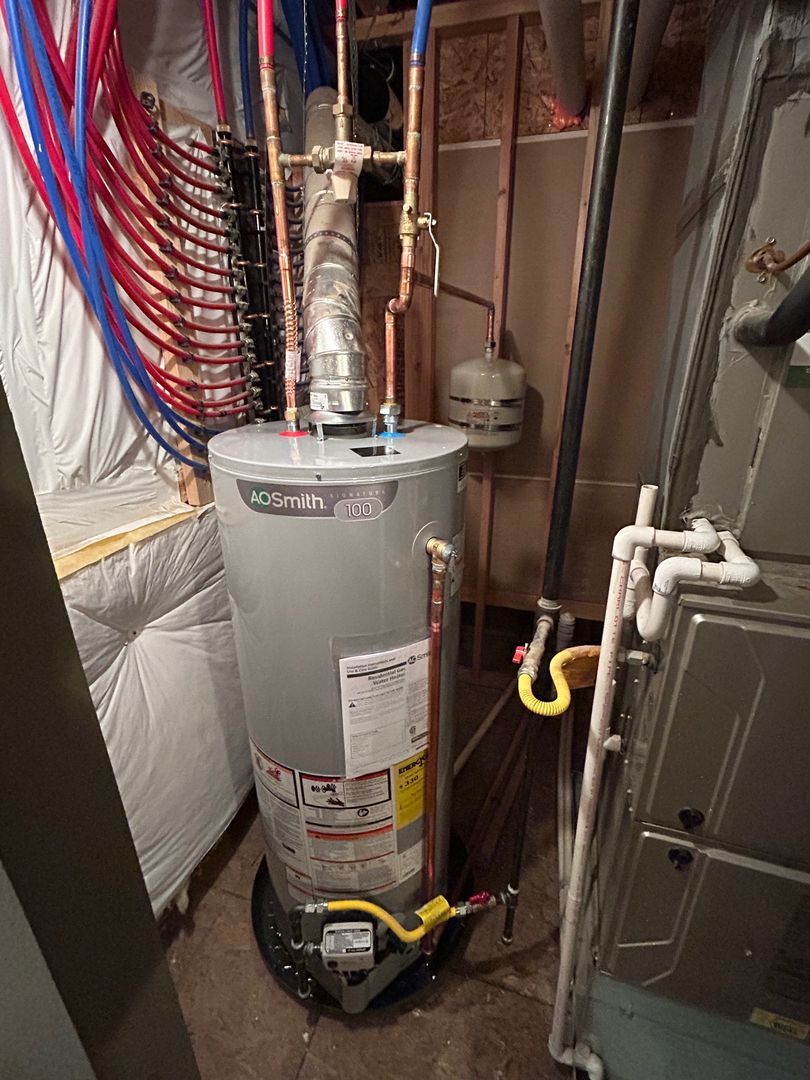 Water heater in a utility closet with exposed pipes, wiring, and insulation.