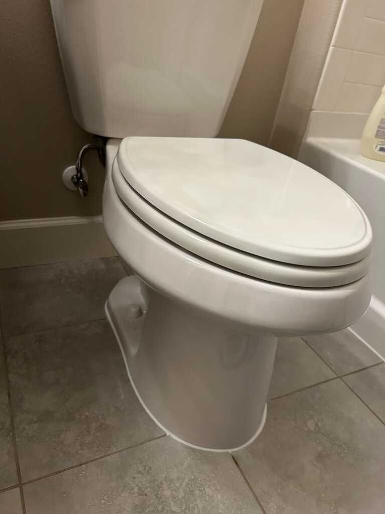 Closed white toilet in a tiled bathroom stall
